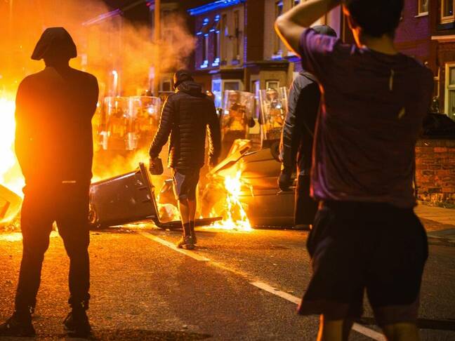 Southport merseyside UK July 30th 2024, protestor stands near burning barricade facing riot police with brick in hand. Southport riot.